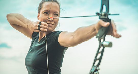 archery, young woman with an arrow in a bow focused on hitting a target